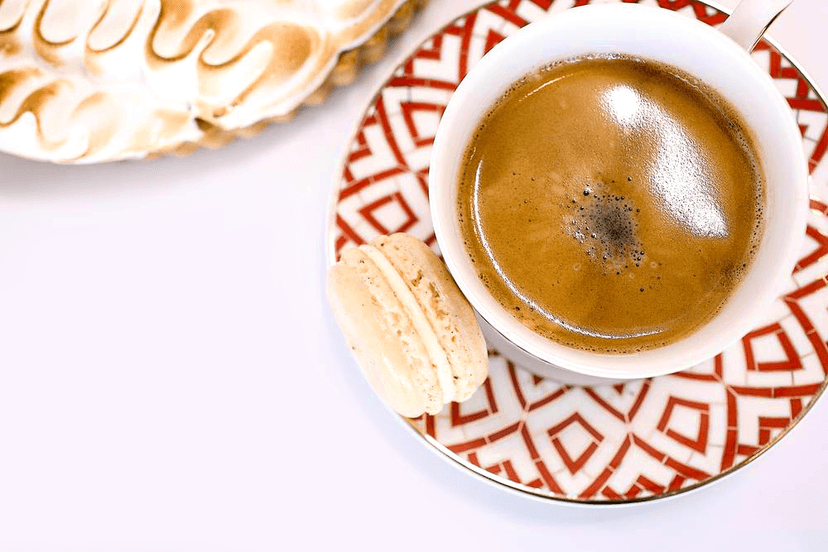 Overhead shot of espresso and macaron on patterned plate